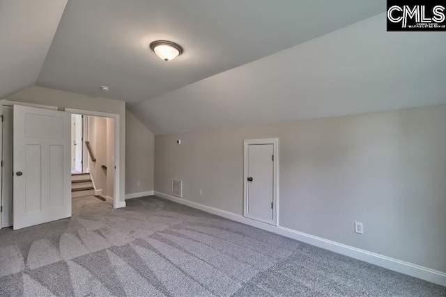 additional living space featuring light colored carpet and vaulted ceiling