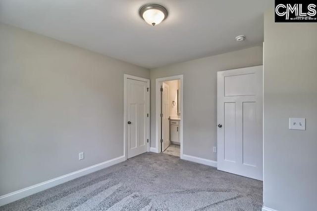 unfurnished bedroom with ensuite bath and light carpet