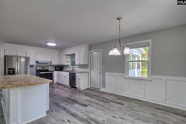 kitchen with light wood-type flooring, appliances with stainless steel finishes, pendant lighting, sink, and white cabinets