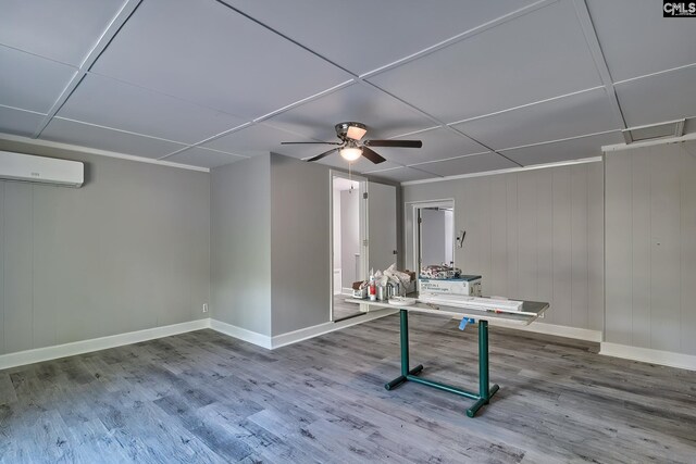 game room featuring wood walls, a wall unit AC, hardwood / wood-style floors, and ceiling fan