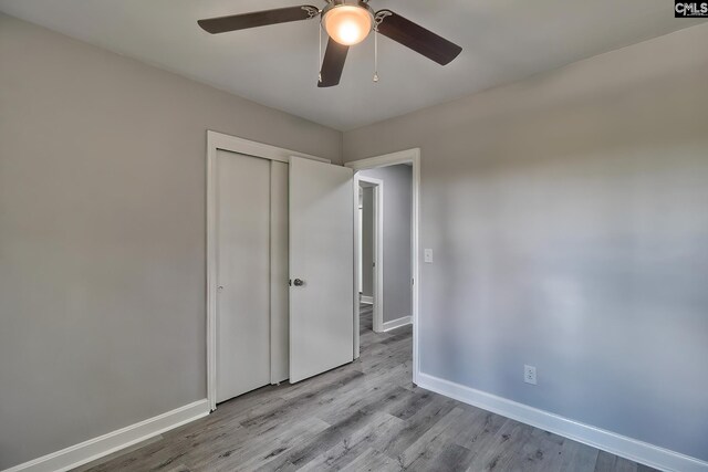 unfurnished bedroom featuring light wood-type flooring, ceiling fan, and a closet