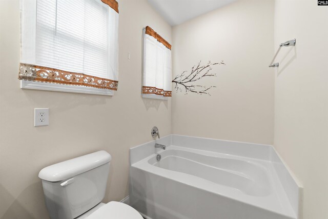 bathroom with a tub to relax in and toilet