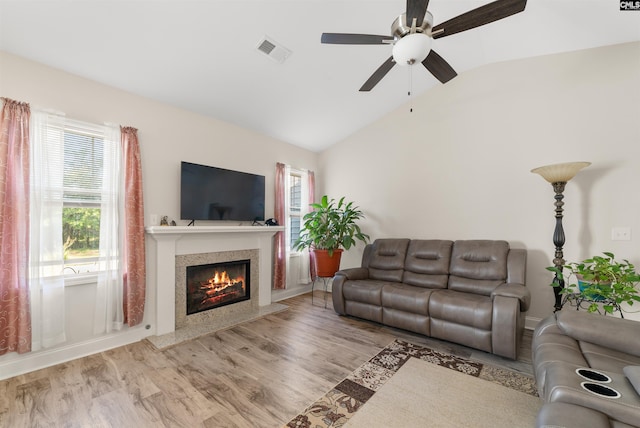 living room with a premium fireplace, light hardwood / wood-style flooring, lofted ceiling, and ceiling fan