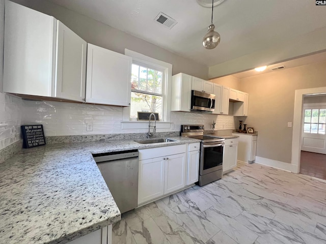 kitchen with stainless steel appliances, backsplash, light stone countertops, sink, and white cabinets