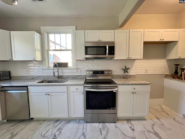 kitchen featuring white cabinets, sink, appliances with stainless steel finishes, and tasteful backsplash