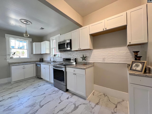 kitchen with stainless steel appliances, white cabinets, sink, and tasteful backsplash