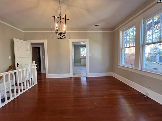 unfurnished dining area featuring ornamental molding, dark hardwood / wood-style flooring, and an inviting chandelier