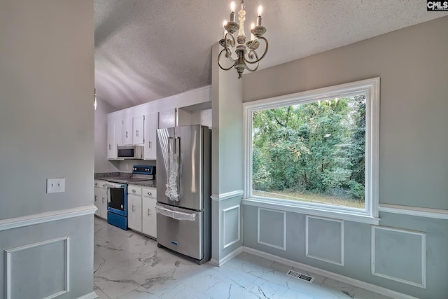 kitchen featuring white cabinetry, appliances with stainless steel finishes, a textured ceiling, and an inviting chandelier