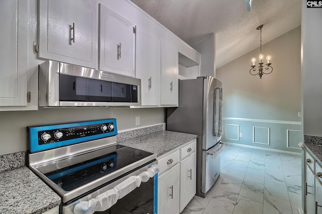 kitchen with stainless steel appliances, a textured ceiling, an inviting chandelier, vaulted ceiling, and white cabinets