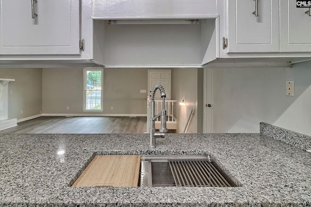 kitchen featuring white cabinets, wood-type flooring, sink, and stone countertops