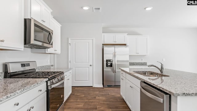 kitchen featuring white cabinets, stainless steel appliances, a kitchen island with sink, and sink