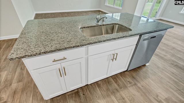 kitchen with dishwasher, stone countertops, an island with sink, and sink