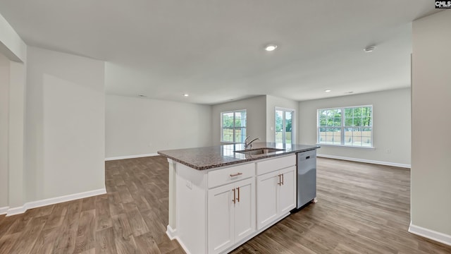 kitchen with white cabinetry, dishwasher, sink, light hardwood / wood-style floors, and a kitchen island with sink