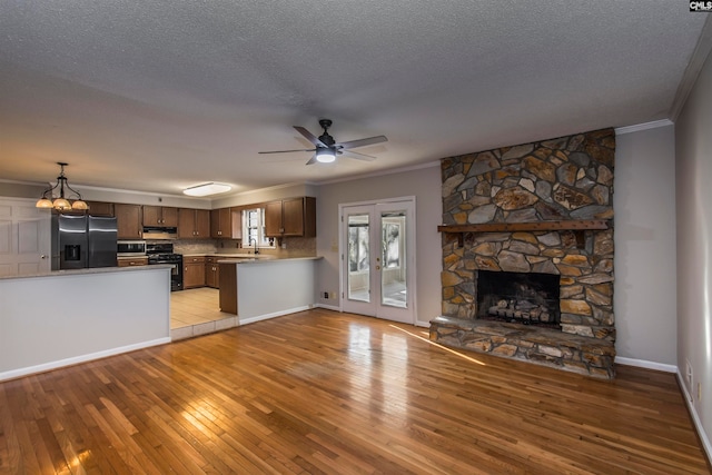 kitchen featuring a fireplace, crown molding, appliances with stainless steel finishes, kitchen peninsula, and light hardwood / wood-style flooring