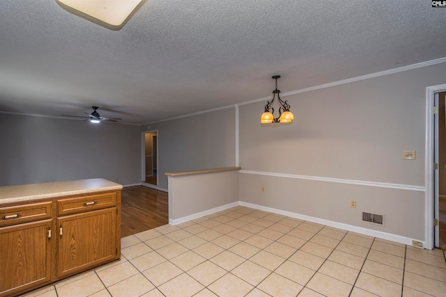 kitchen with light tile patterned flooring, crown molding, a textured ceiling, hanging light fixtures, and ceiling fan with notable chandelier