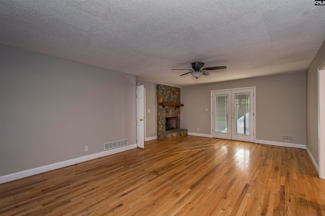 unfurnished living room featuring a textured ceiling, a fireplace, light hardwood / wood-style floors, and ceiling fan