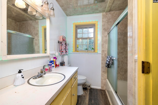 full bathroom with hardwood / wood-style floors, vanity, toilet, and bath / shower combo with glass door