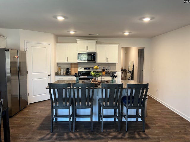 kitchen featuring white cabinetry, a kitchen island with sink, a kitchen breakfast bar, and stainless steel appliances