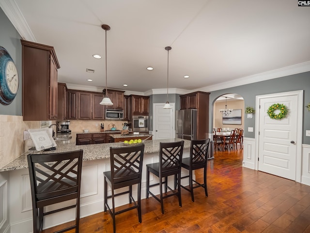 kitchen featuring stainless steel appliances, light stone countertops, hanging light fixtures, sink, and dark wood-type flooring