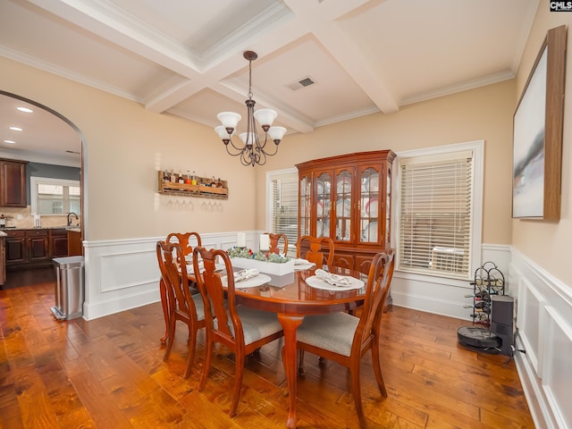 dining room with ornamental molding, beamed ceiling, wood-type flooring, and sink