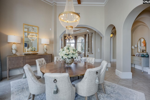 dining area featuring decorative columns, a notable chandelier, ornamental molding, and a towering ceiling