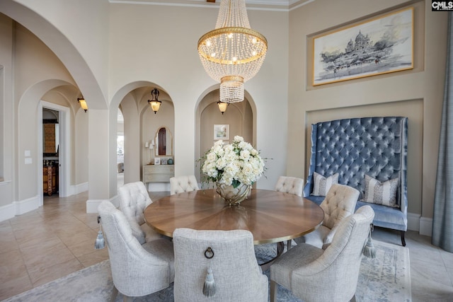 tiled dining area with a high ceiling, a notable chandelier, and ornamental molding