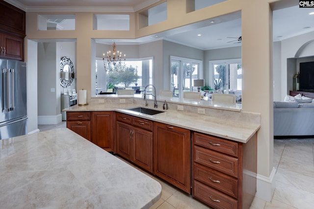 kitchen with sink, ceiling fan with notable chandelier, ornamental molding, and high end fridge