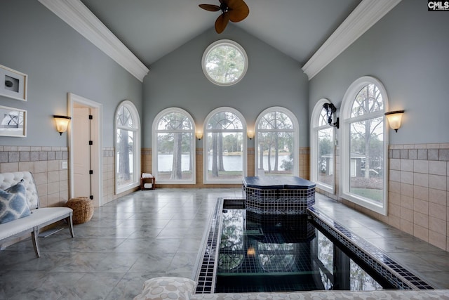 living room with ceiling fan, a healthy amount of sunlight, and tile walls