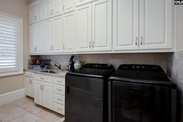 laundry room with cabinets, light tile patterned flooring, washer and dryer, and sink