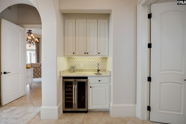 bar with beverage cooler, light tile patterned floors, and backsplash