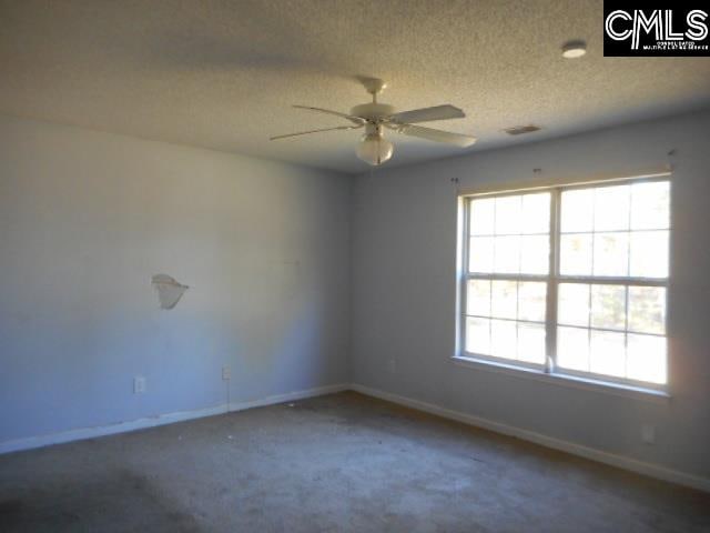 carpeted empty room with ceiling fan and a textured ceiling