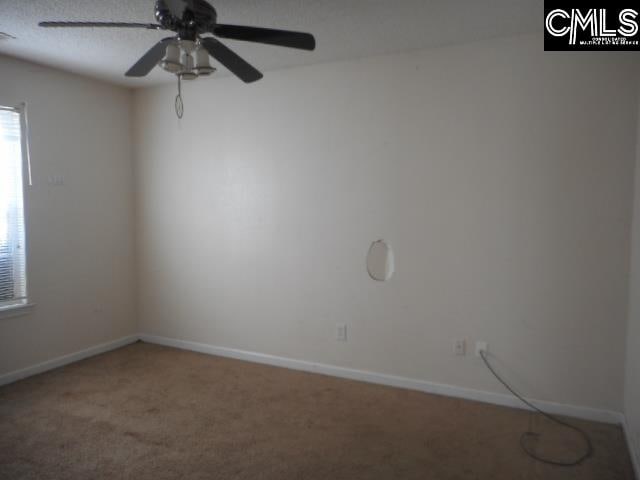 spare room with a textured ceiling, carpet floors, and ceiling fan