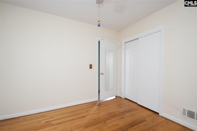 unfurnished bedroom with a closet, a textured ceiling, and light hardwood / wood-style flooring