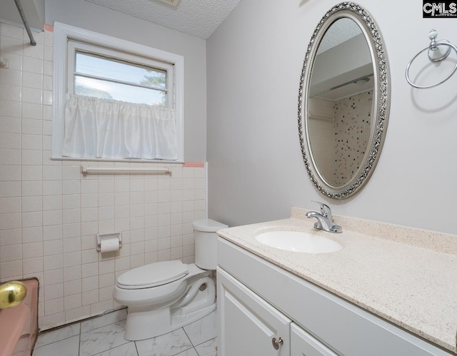 bathroom with toilet, vanity, tile walls, and a textured ceiling