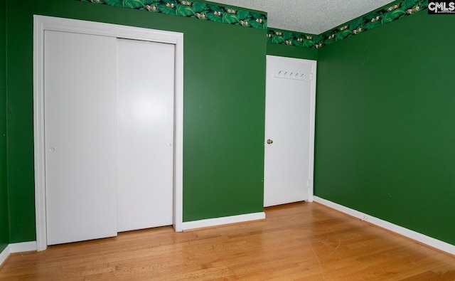 unfurnished bedroom with a closet, hardwood / wood-style floors, and a textured ceiling