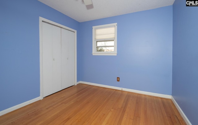 unfurnished bedroom with light hardwood / wood-style flooring, a textured ceiling, ceiling fan, and a closet