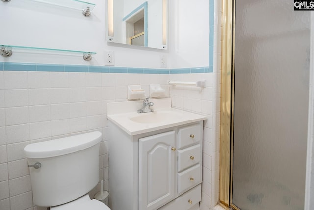 bathroom with toilet, vanity, and tile walls