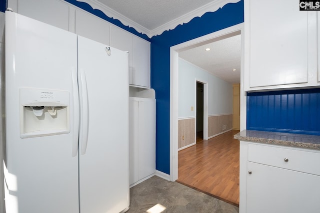 kitchen with white cabinets, a textured ceiling, crown molding, and white refrigerator with ice dispenser