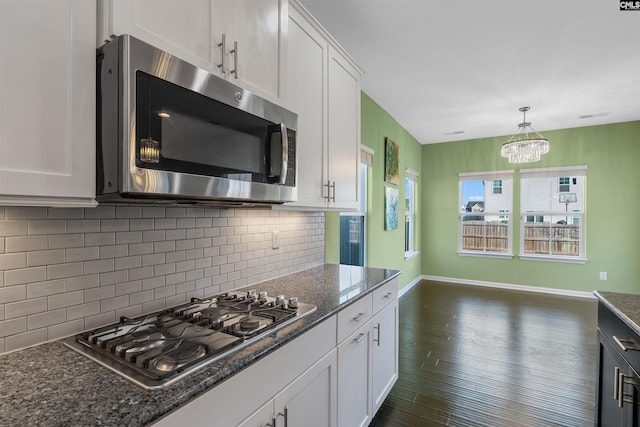 kitchen featuring white cabinets, appliances with stainless steel finishes, and dark stone countertops