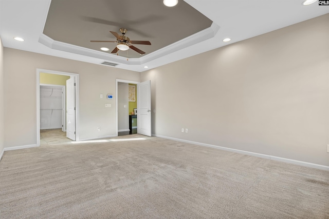 unfurnished room featuring ceiling fan, light carpet, crown molding, and a tray ceiling