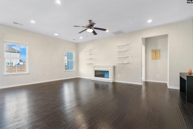 unfurnished living room featuring dark wood-type flooring and ceiling fan