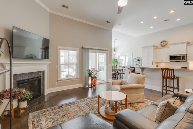 living room with a fireplace, plenty of natural light, dark wood-type flooring, and ornamental molding