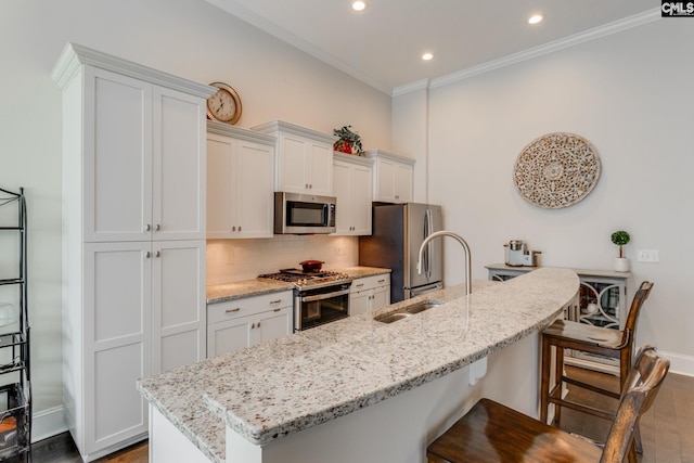 kitchen featuring a kitchen breakfast bar, white cabinetry, dark hardwood / wood-style flooring, and appliances with stainless steel finishes