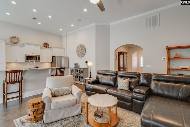 living room with crown molding, sink, ceiling fan, and light hardwood / wood-style floors