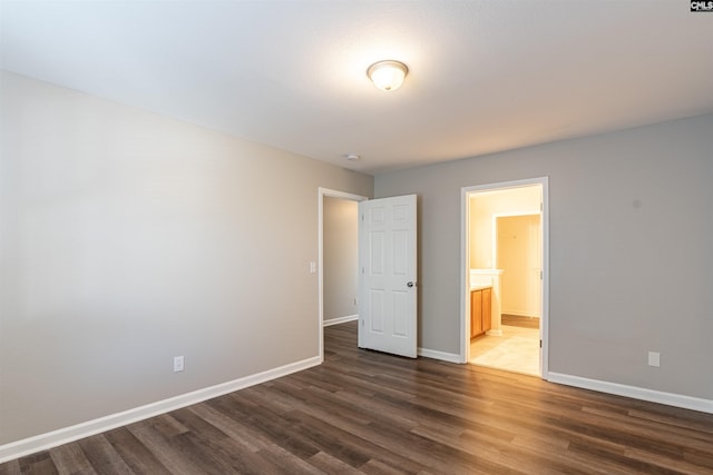 unfurnished bedroom featuring dark hardwood / wood-style floors and ensuite bathroom