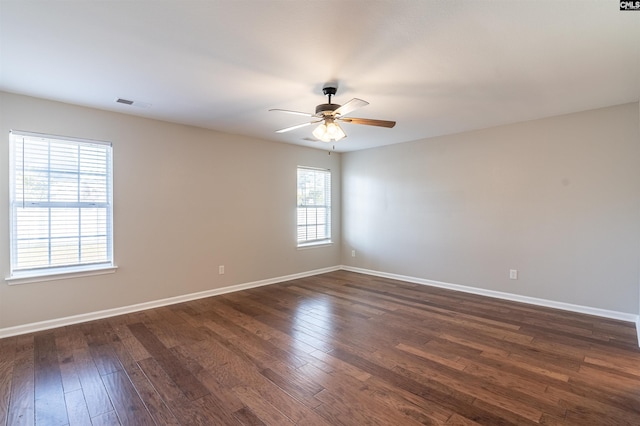 empty room with dark hardwood / wood-style floors, plenty of natural light, and ceiling fan