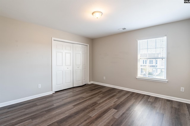 unfurnished bedroom featuring dark hardwood / wood-style flooring and a closet