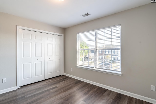 unfurnished bedroom featuring a closet and dark hardwood / wood-style flooring