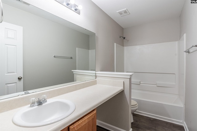 full bathroom with washtub / shower combination, hardwood / wood-style floors, vanity, and toilet