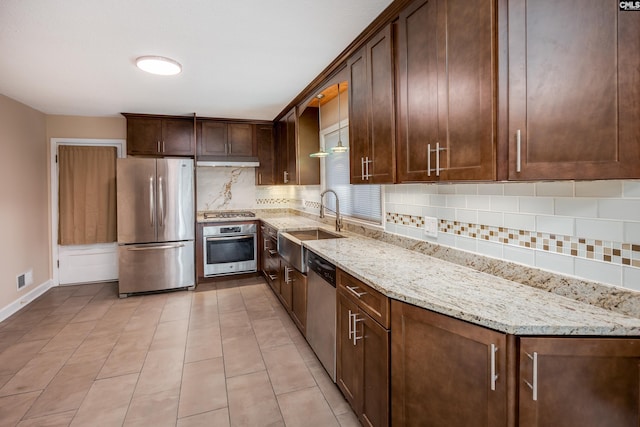 kitchen featuring light stone countertops, sink, stainless steel appliances, backsplash, and light tile patterned floors